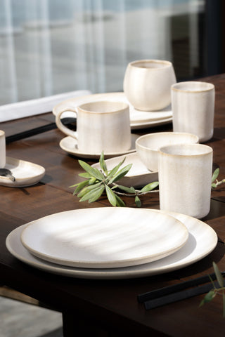 A dark wooden table set with Sand Storm stoneware plates, mugs and a jug